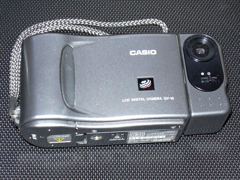 The 1995 Casio QV-10 camera, grey, with the lens mounted on a swivelling body on the right and the words LCD DIGITAL CAMERA QV-10 printed on the front.